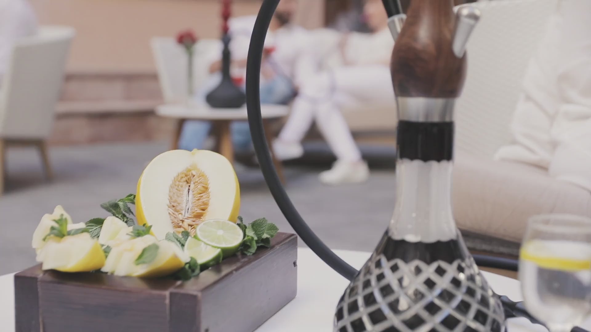 Lifestyle video of a woman in white enjoying shisha from a walnut Wookah pipe, creating a calm, elegant mood.
