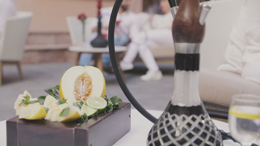 Lifestyle video of a woman in white enjoying shisha from a walnut Wookah pipe, creating a calm, elegant mood.